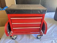 Front view showing red tool chest with four drawers, side handles, casters