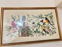 Full view of framed embroidery showing birds and foliage