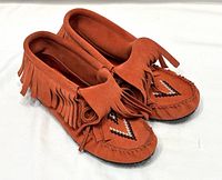 Angled view of both boots showing fringe, beadwork, overall condition