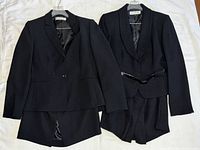 Both black blazers with skirts on hangers