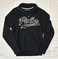 Full front view of dark charcoal quarter-zip sweater with white Polo script