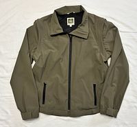 Front view of olive green Tilley nylon jacket with full zipper and pockets