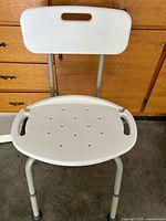 Front view of chair showing seat, backrest, aluminum legs, drainage holes, handles