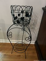 Full view of black wrought iron plant stand showing removable basket and lower shelf