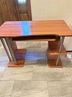 Front view of cherry laminate computer desk showing keyboard tray, shelves, metal legs