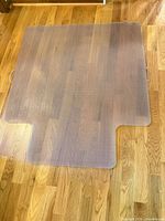 Full view of clear vinyl chair mat showing rectangular shape, desk cutouts, and surface condition