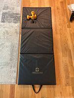 Tri-fold Harbinger mat fully opened with pair of yellow dumbbells placed on top