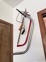 Three bow saws hanging on wall, showing frames, handles and blades