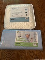 Front view of Sleep Tite mattress protector package and sealed 4-pack underpads