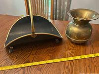 Coal scuttle and brass urn on table with tape measure for scale