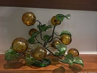 Front view of amber and green glass fruit sculpture on shelf