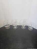 Four clear glass brandy snifters in descending size order