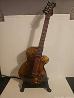 Full view of amber guitar lamp on stand with power cord visible