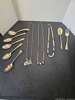 Overall lot showing three necklaces and seven utensils