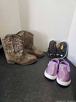 All three pairs of footwear displayed: cowboy boots, black slip-ons, purple glitter sneakers