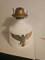 Front view of white milk glass oil lamp with eagle graphic and brass burner