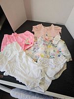 All garments laid out: floral dress with diaper cover and five onesies