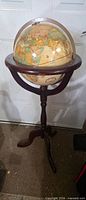 Full view of globe on wooden pedestal tripod stand