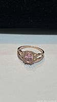 ring front view showing pink center stone, halo, and split shoulders