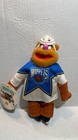 Front view of Fozzie Bear plush wearing hockey jersey