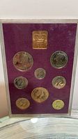 Obverse sides of nine coins and Royal Mint plaque in case