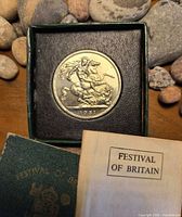 Coin in green Royal Mint box with rocks background and leaflet visible
