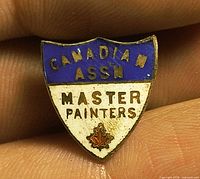 Front view of enamel shield pin showing text and maple leaf