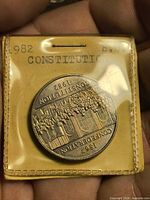 Reverse side of 1982 Canadian Constitution dollar in sealed flip showing building and inscription