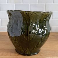 Front view of green glazed jardiniere showing molded leaf pattern and scalloped rim