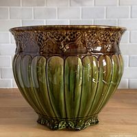 Side view showing ribbed green body and brown rim scrollwork