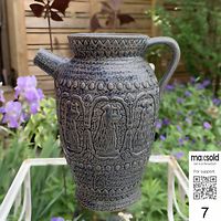 Front view of blue stoneware pitcher showing lyre player relief and handle