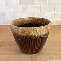 Front view of brown drip glaze stoneware planter showing ribbed body and drip rim