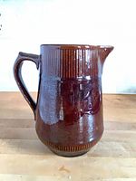 front view of pitcher showing handle, ribbed rim and glaze