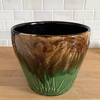 Front view of stoneware planter showing brown drip over green glaze and embossed pattern