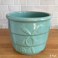 Front view showing ribbed sides and molded floral motif of aqua planter