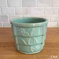 Front view of aqua blue planter showing raised floral pattern