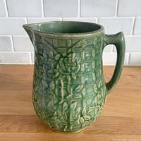 Overall view of green climbing rose pottery pitcher showing condition and design.