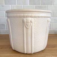 Front view of matte white planter showing strap relief panels and texture