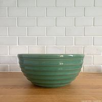 Exterior side view of dark green ribbed ceramic mixing bowl