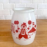 front view showing red clown and circus graphics on white milk glass canister