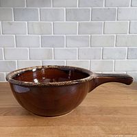 Oblique view of brown drip glaze handled soup bowl on countertop