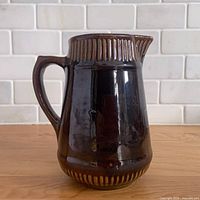 Front view of glossy brown ribbed band stoneware pitcher