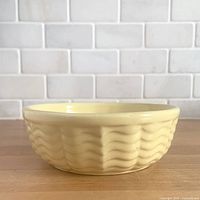 Side view of gloss yellow wave-pattern bowl