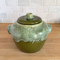 Front view of green drip glazed bean pot with lid