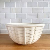 Front view of cream stoneware mixing bowl showing wave pattern