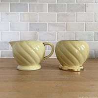front view of creamer and sugar bowl showing swirl pattern and gold trim