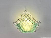Piece shown hung from ceiling with light shining through glass