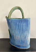 Full side view showing blue exterior glaze, green handle and wavy rim