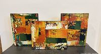 Front view of three mixed-media paintings arranged side by side