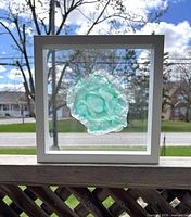 Front view of aqua fused glass artwork in square white frame